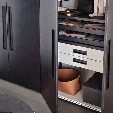A modern wardrobe with black doors featuring minimalistic embedded handles, part of a furniture set possibly in a residential interior.