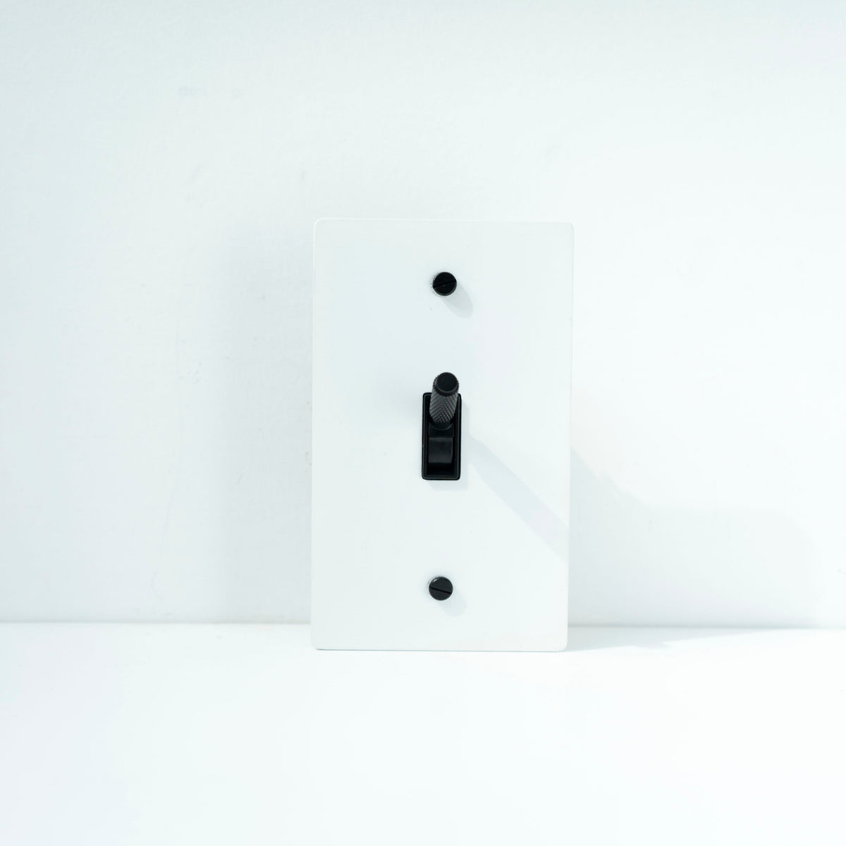 A black brass knurled light switch with a gold-colored toggle and two brass rocker switches on the side.