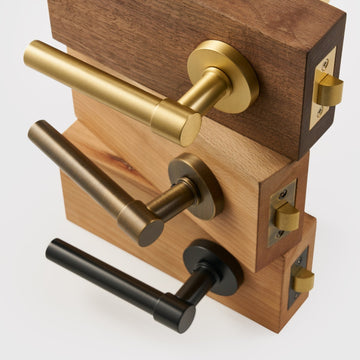 DELOS brass lever door handles in Satin Brass, Antique Brass and Matte Black on wooden door samples