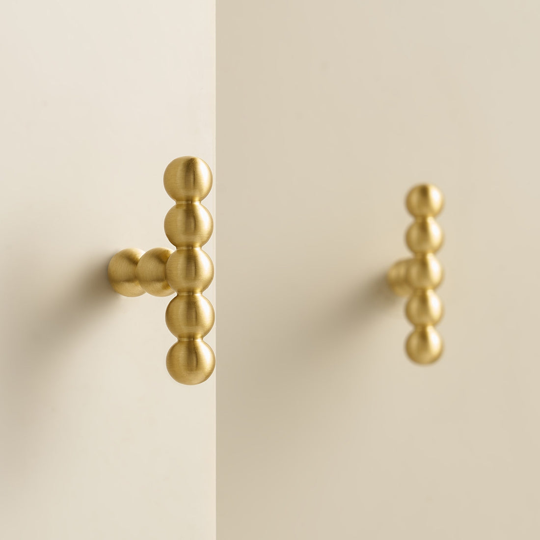 KOMBOLOI beaded brass T-pulls on cream cabinet doors