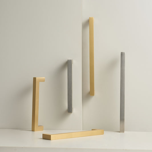 OIA square brass handles in Satin Brass and Brushed Nickel standing on a stone plinth