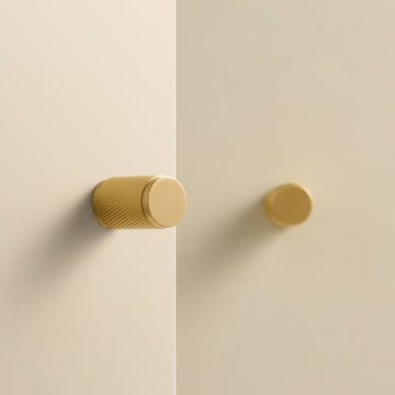 PALENCIA swirled knurl brass knobs in Satin Brass on cream cabinet doors