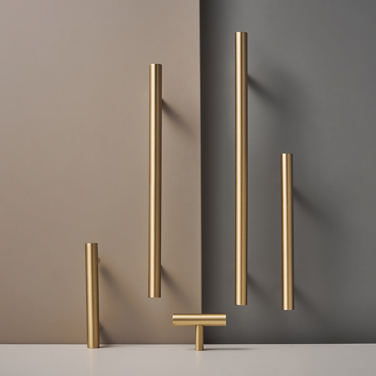 TRACY satin brass handles in several lengths against a two-tone wall
